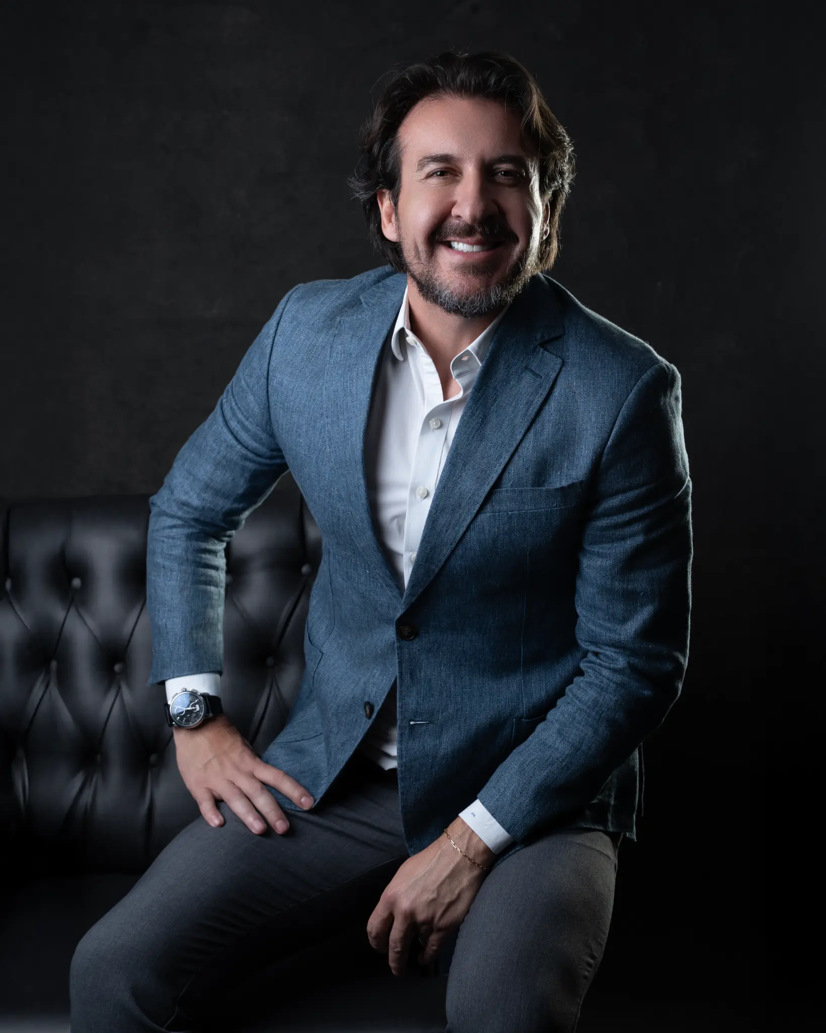 Dr. Jacques Souza sorrindo no sofá